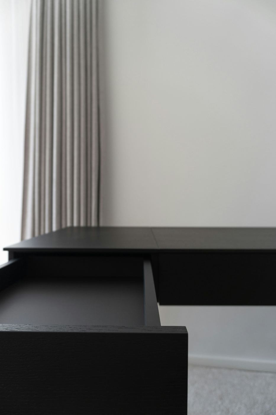 Built-in home office desk with drawers set beneath a window and shelving alongside